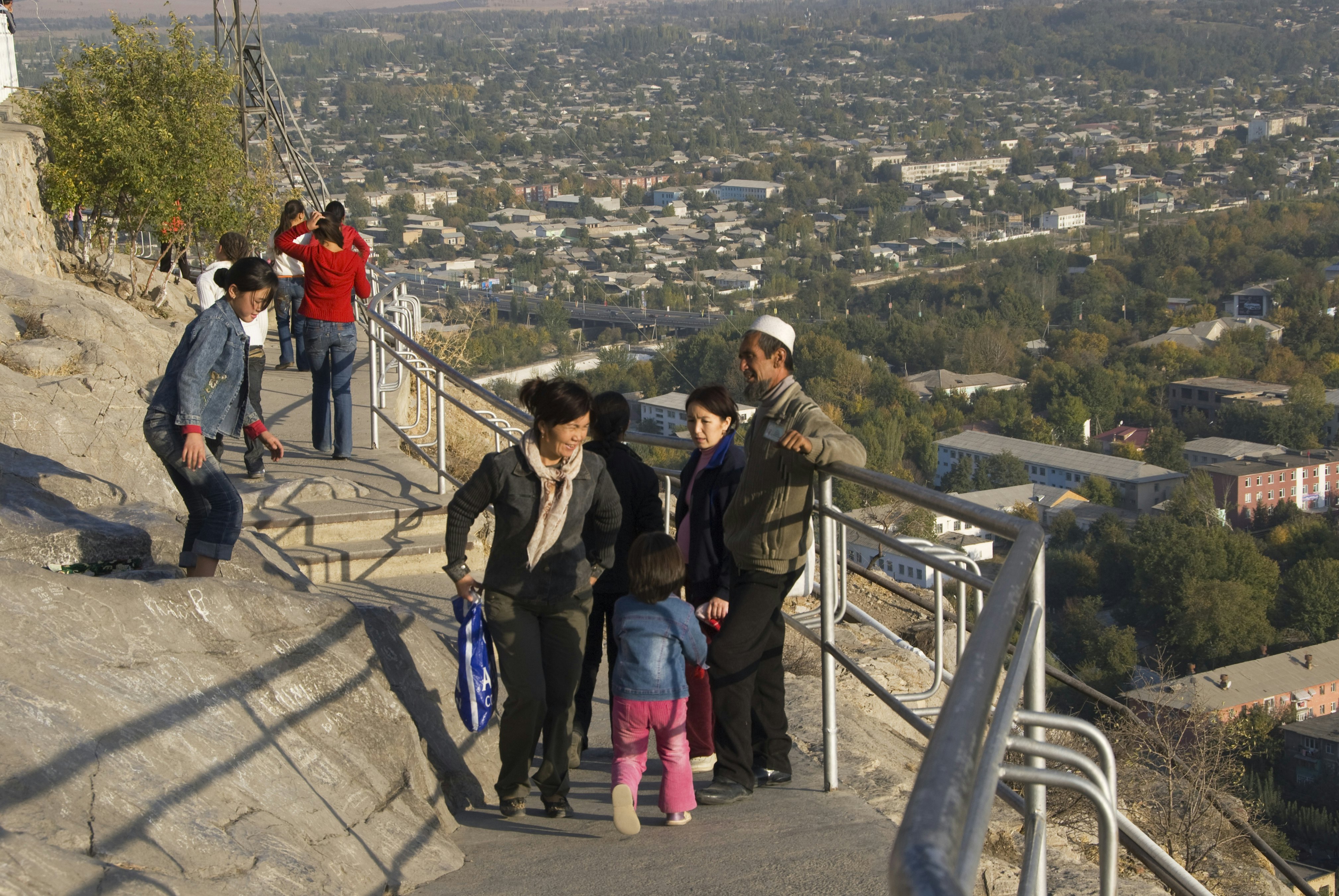 Kyrgyz people enjoying themselves on Solomon's Throne with city overview.
