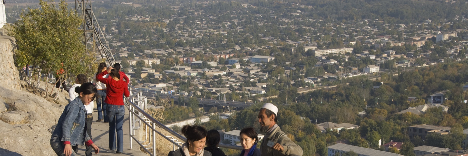 Kyrgyz people enjoying themselves on Solomon's Throne with city overview.