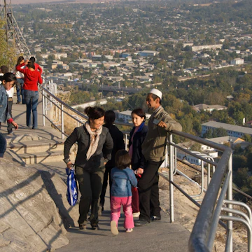 Kyrgyz people enjoying themselves on Solomon's Throne with city overview.