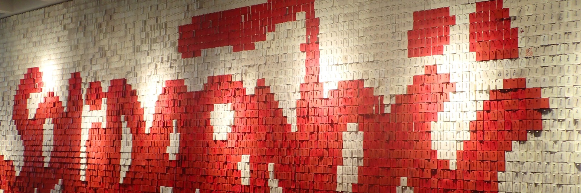 Wall spelling out the Solidarity logo in Polish, composed of small red and white pieces of card.
