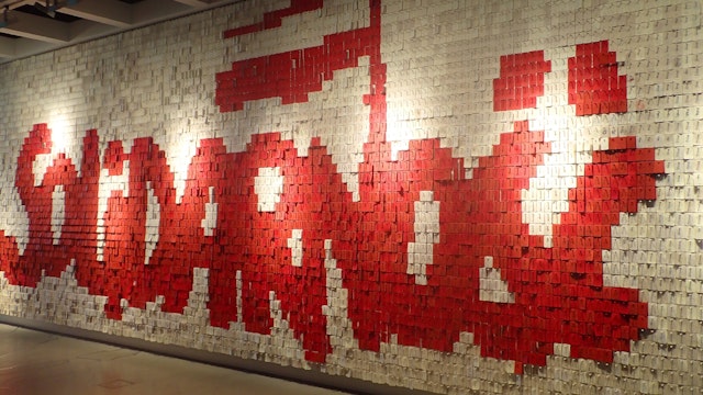 Wall spelling out the Solidarity logo in Polish, composed of small red and white pieces of card.