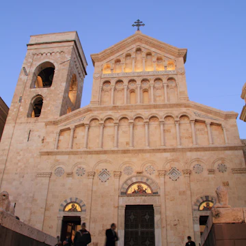 People on steps in front of Cattedrale di Santa Maria at dusk.