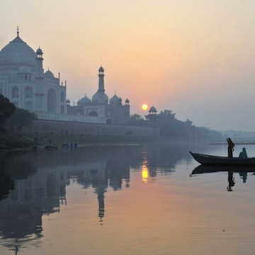 Boat paddling past Taj Mahal on Yamuna River.