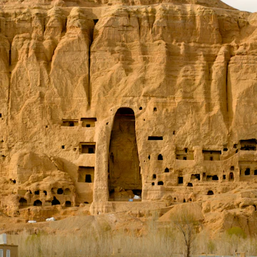People standing near Buddha in rockface.