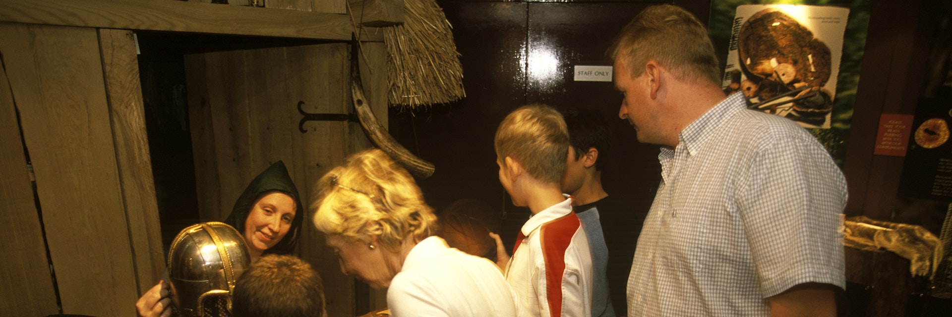 A family watch on as a woman in traditional dress demonstrating stitching at the Jorvik Viking Centre in York.