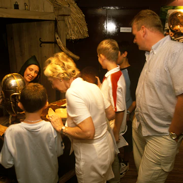 A family watch on as a woman in traditional dress demonstrating stitching at the Jorvik Viking Centre in York.