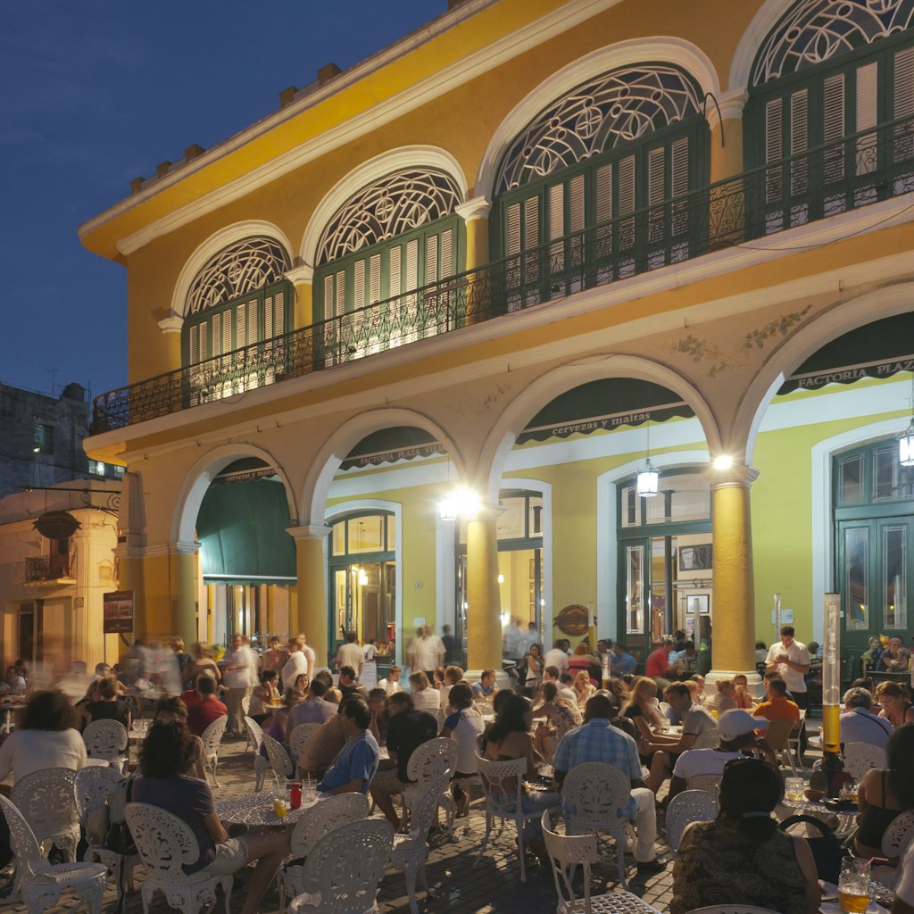 Plaza Vieja, bustling with restaurants and cafes in evening.