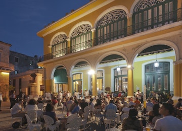 Plaza Vieja, bustling with restaurants and cafes in evening.