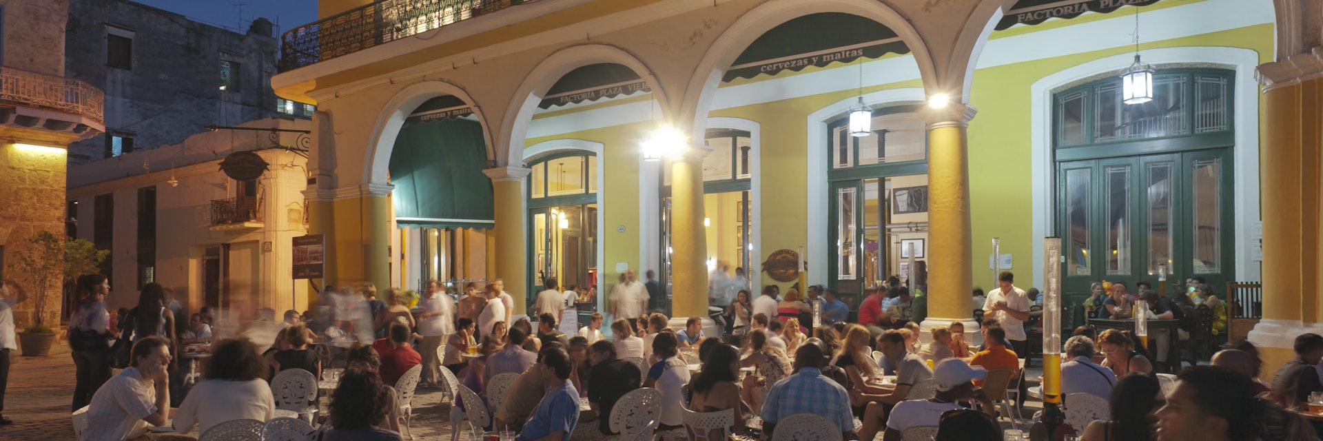 Plaza Vieja, bustling with restaurants and cafes in evening.