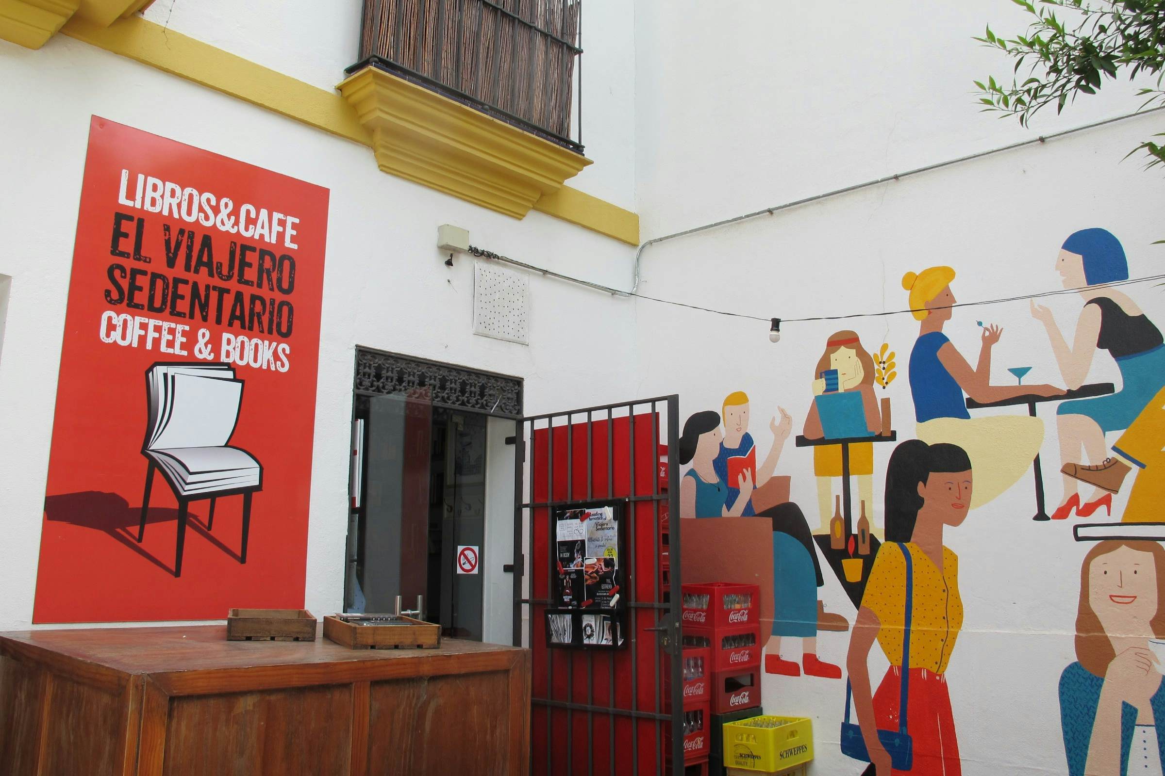 Door with sign and paintings on wall, El Viajero Sedentario coffee and books cafe.