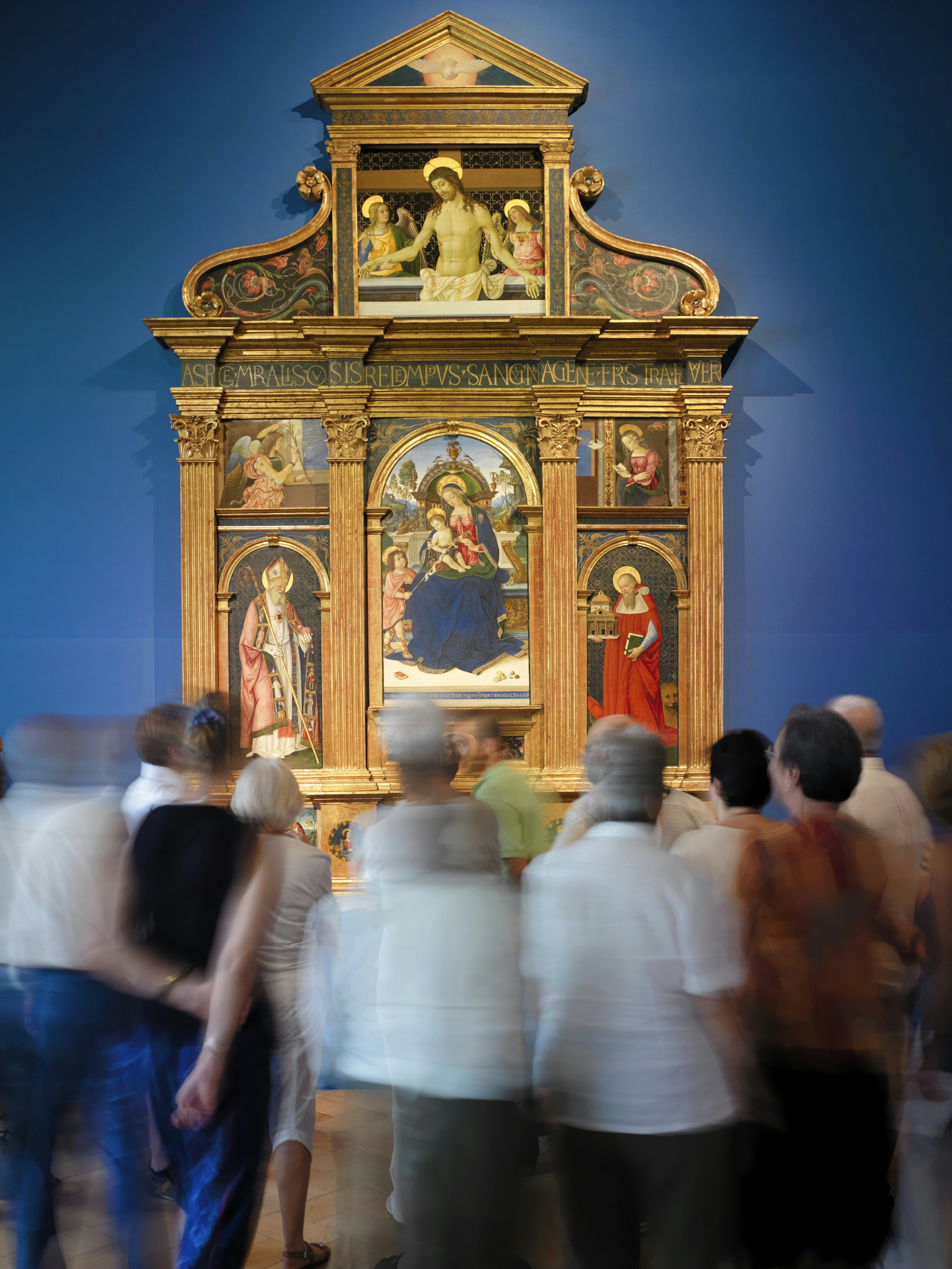 Tourist admire Pintoricchio's Pala di Santa Maria dei Fossi(1495)  in the National Gallery of Umbria.(Galleria Nazionale dell'Umbria). In the center of the multipaneled painting, the Madonna holds baby Jesus on her lap and a Pomergrante in the other hand.