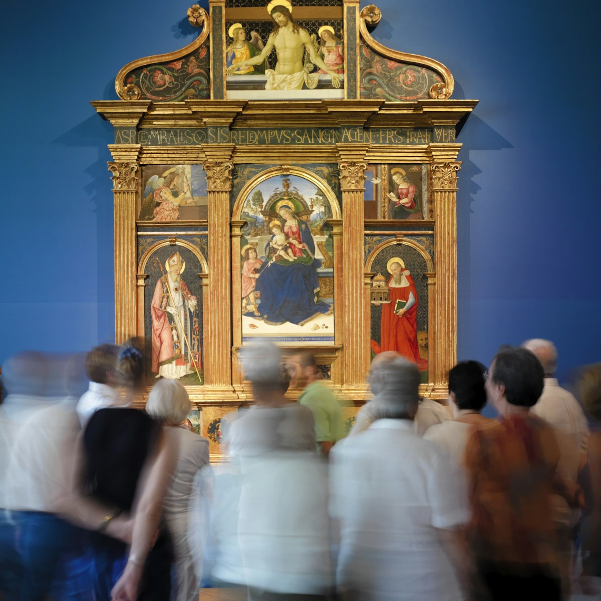 Tourist admire Pintoricchio's Pala di Santa Maria dei Fossi(1495)  in the National Gallery of Umbria.(Galleria Nazionale dell'Umbria). In the center of the multipaneled painting, the Madonna holds baby Jesus on her lap and a Pomergrante in the other hand.