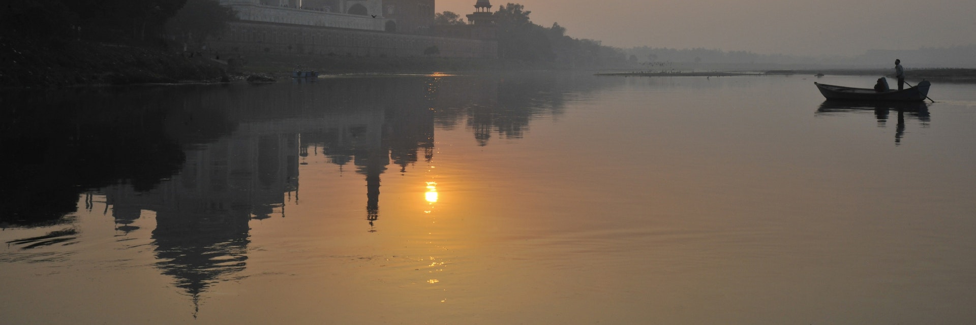 Boat padding on Yamuna River beside Taj Mahal.
