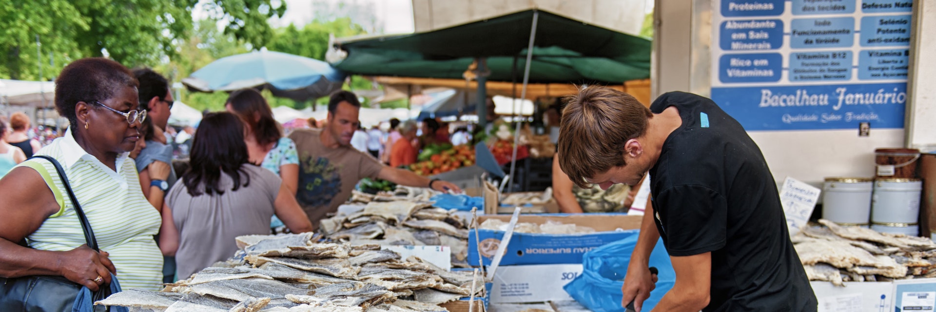 Barcelos, Portugal - August 23, 2012: A man is cutting bacalhau during the market day. Bacalhau dishes are very common in Portugal.; Shutterstock ID 241520329; Your name (First / Last): Tom Stainer; GL account no.: 65050 ; Netsuite department name: Online Editorial; Full Product or Project name including edition: Best in Travel 2018