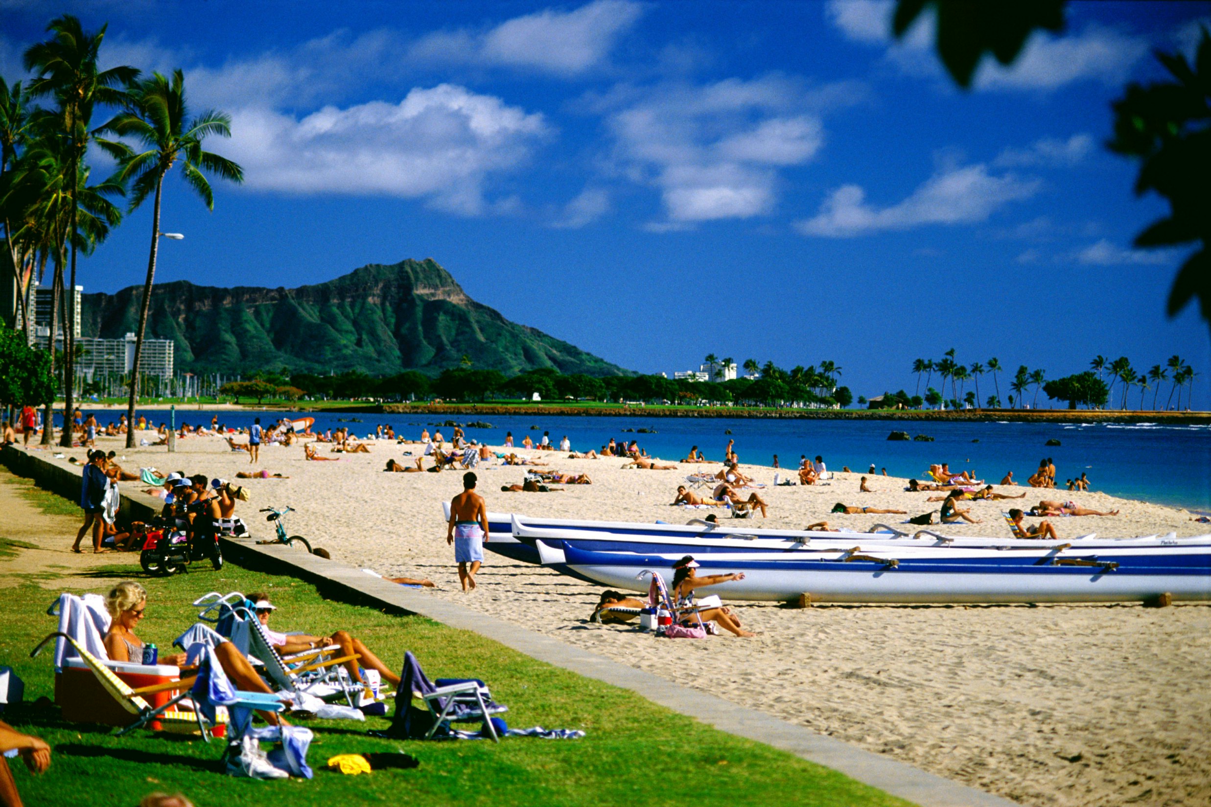 Visitors crowd beaches at Ala Moana Beach Park, Diamond Head background