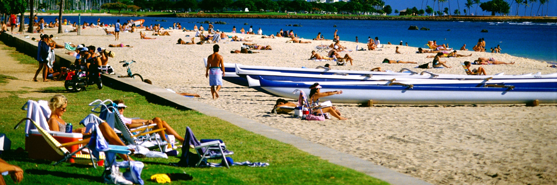 Visitors crowd beaches at Ala Moana Beach Park, Diamond Head background