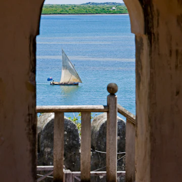 Kenya, Lamu Island, Lamu. A sailing boat (mashua) framed in an arch of Lamu Fort, which is now a museum.