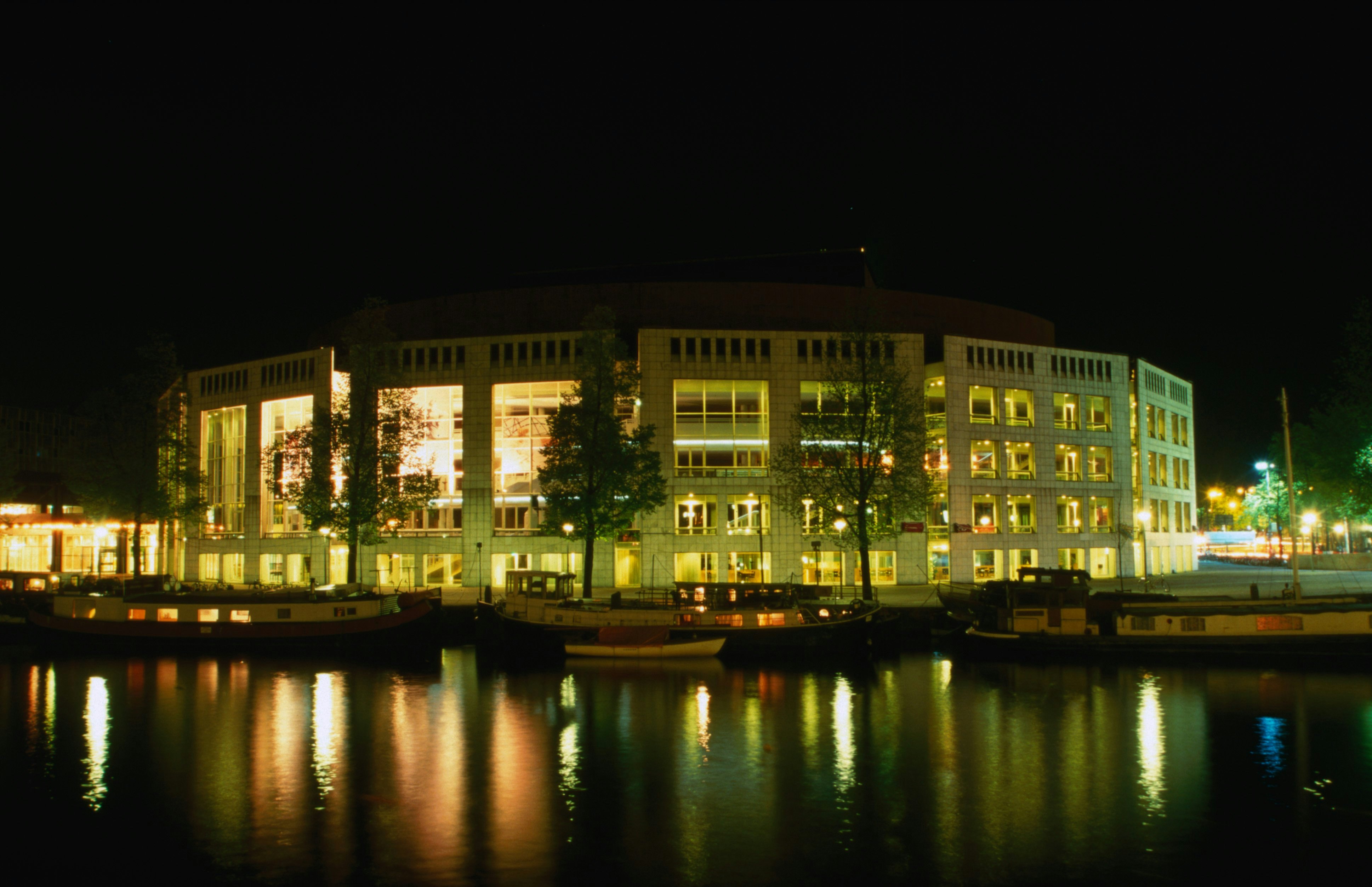 The Stopera, a City Hall and music theatre on Waterlooplein by the Binnen Amstel, at night.