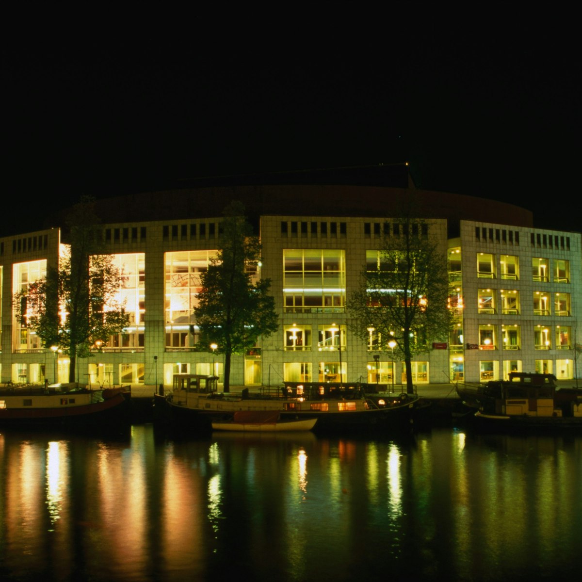 The Stopera, a City Hall and music theatre on Waterlooplein by the Binnen Amstel, at night.