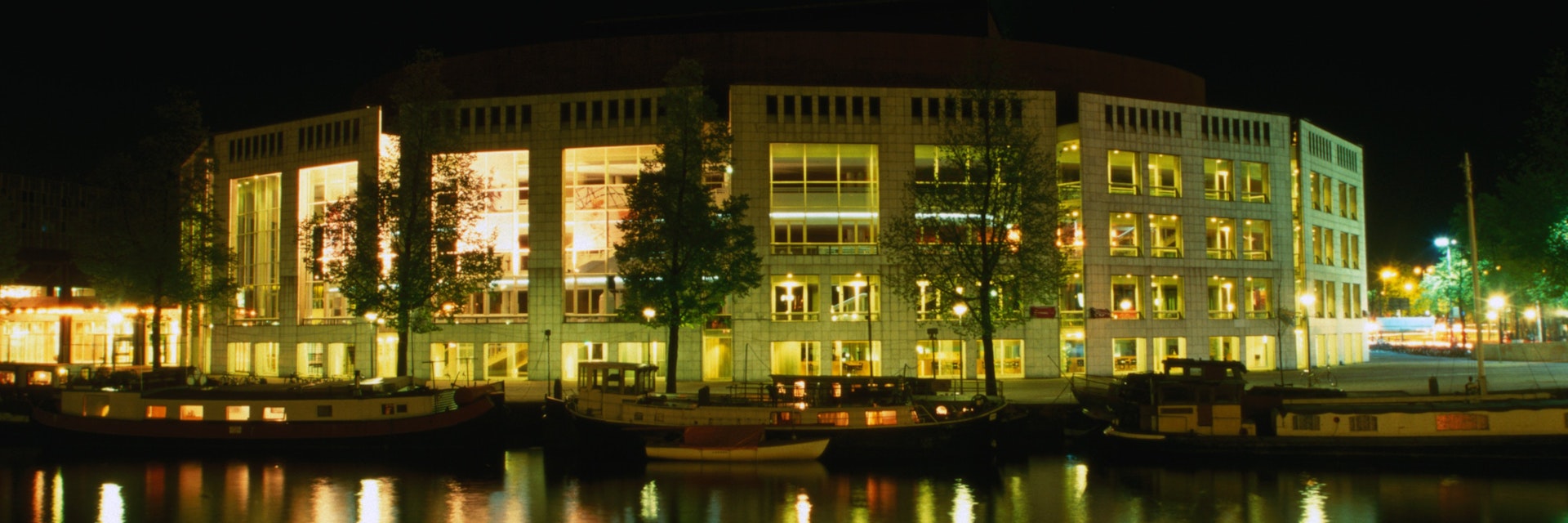 The Stopera, a City Hall and music theatre on Waterlooplein by the Binnen Amstel, at night.