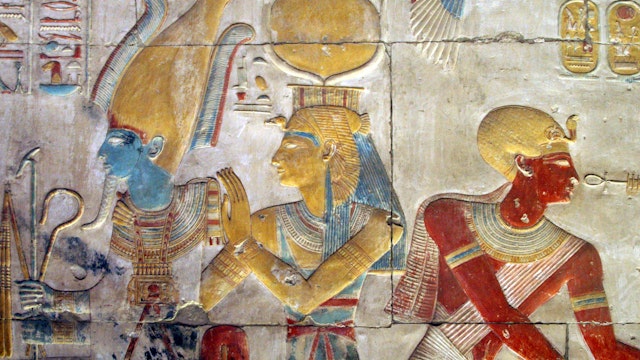 Painted bas relief of Osiris and Isis wearing the headdress of Hathor. The Great Temple of Seti I.Abydos, Sohag Governorate,Egypt.
