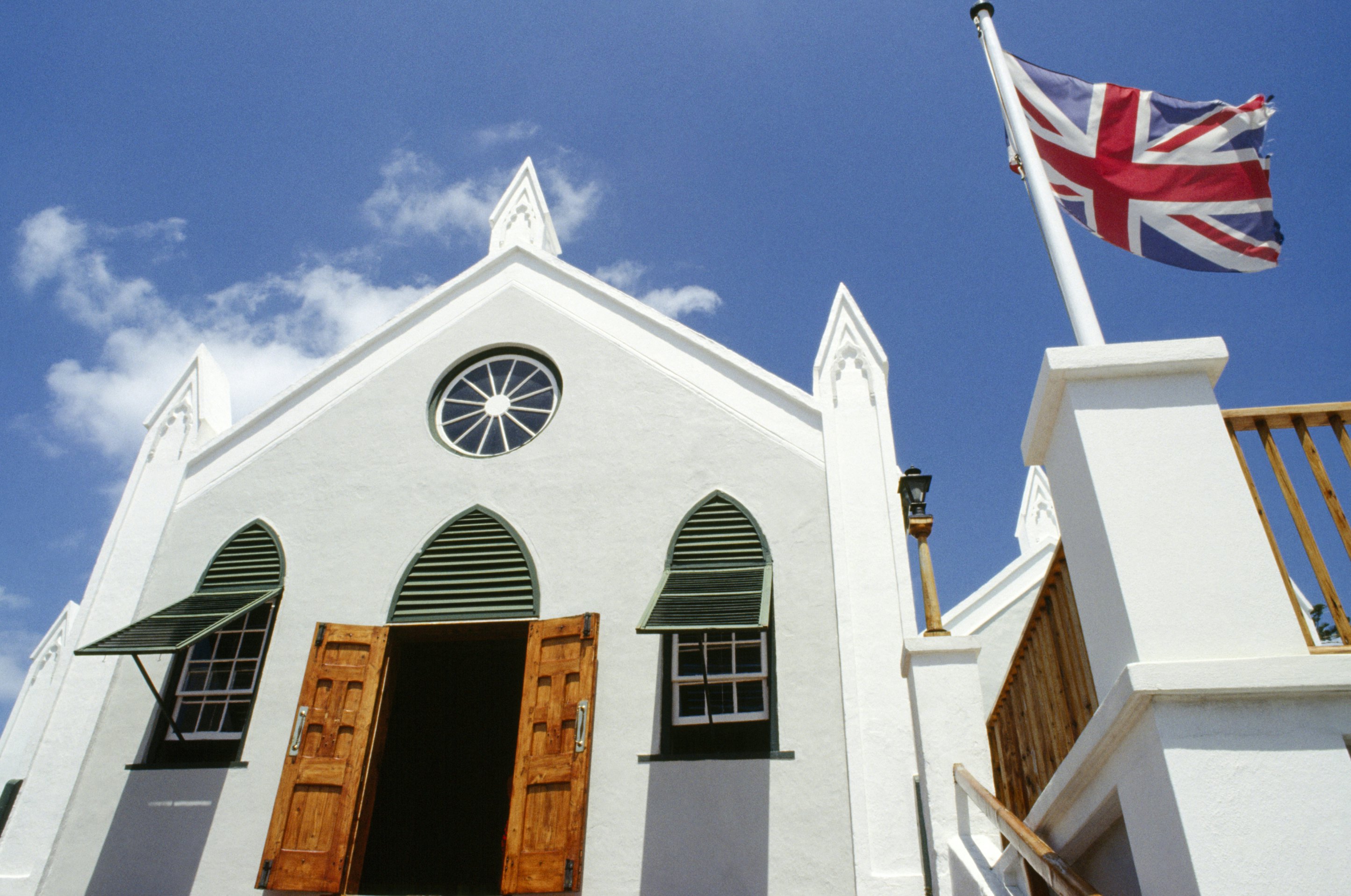 bermuda, st george s island, st. georges, st peters church facade with open door and windows, british union jack flag flying outside.