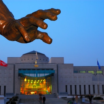 Hand of statue in front of War Memorial at dusk.