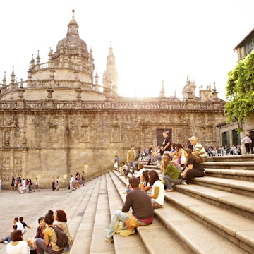 Visitors sitting on steps outside Santiago de Compostela Cathedral.