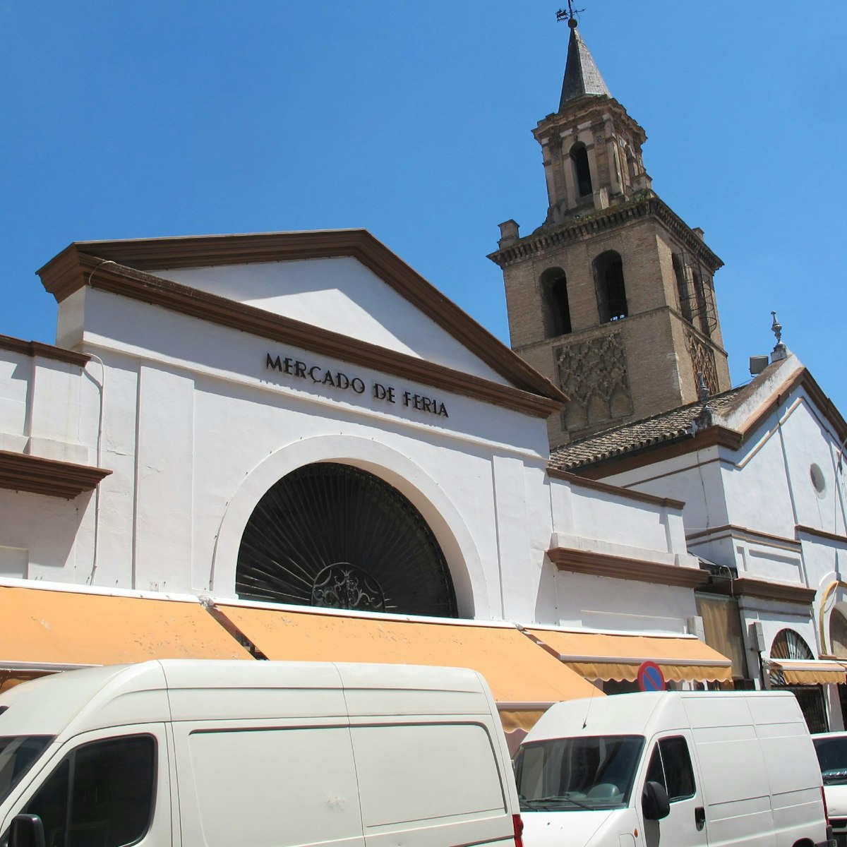Market facade with vans and church, Mercado de Feria.