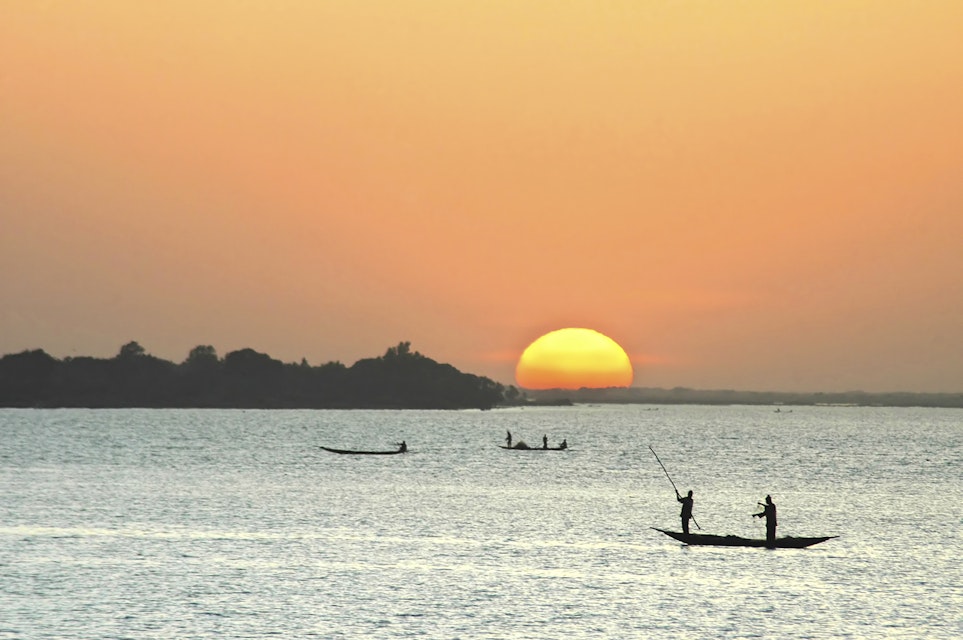 African fishermen silhouetted in canoes at sunset