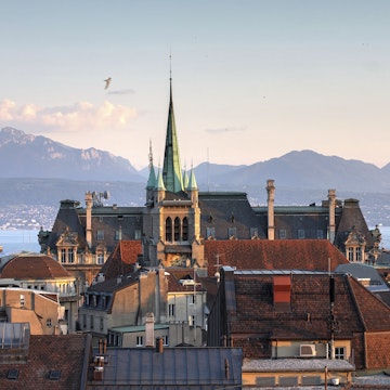 Skyline of Lausanne, Switzerland as seen from the Cathedral hill at sunset zoomed-in on the tower of St-Francois Church. Lake Leman (Lake Geneva) and the French Alps provide a beautiful background.