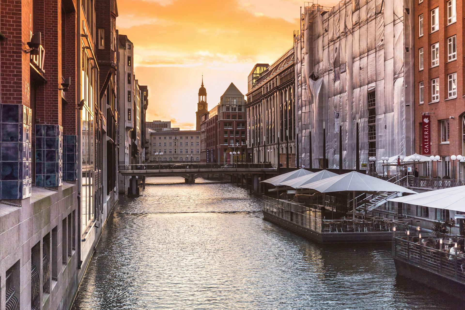 A view down the river in Hamburg with tall beautiful architecture on either side and the sun setting behind it; Copenhagen alternatives