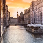 A view down the river in Hamburg with tall beautiful architecture on either side and the sun setting behind it; Copenhagen alternatives