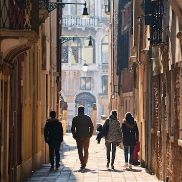A group of people walk through a narrow alleyway in Venice