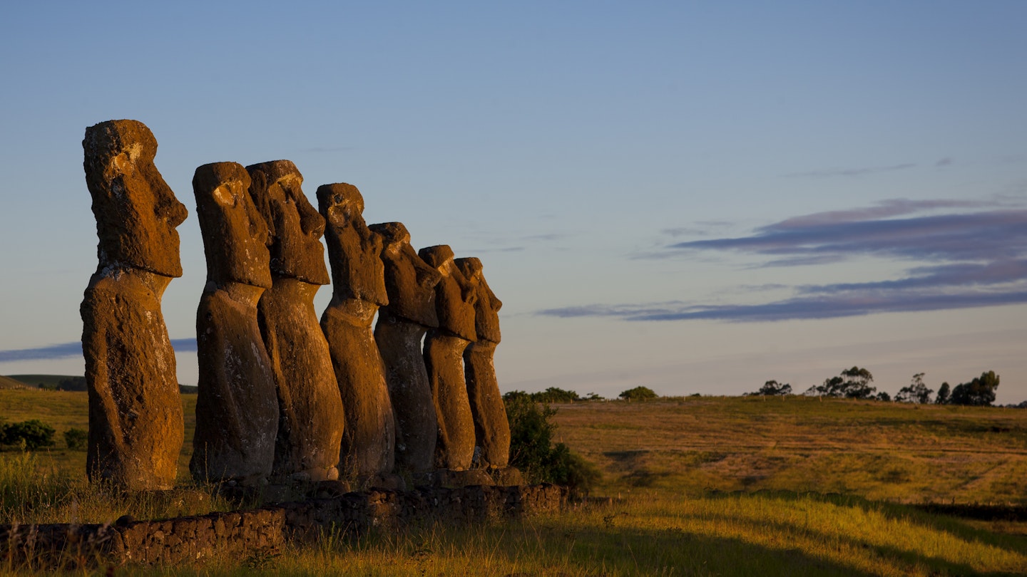 Easter Island statues in a line as the sun sets on Rapa Nui. 