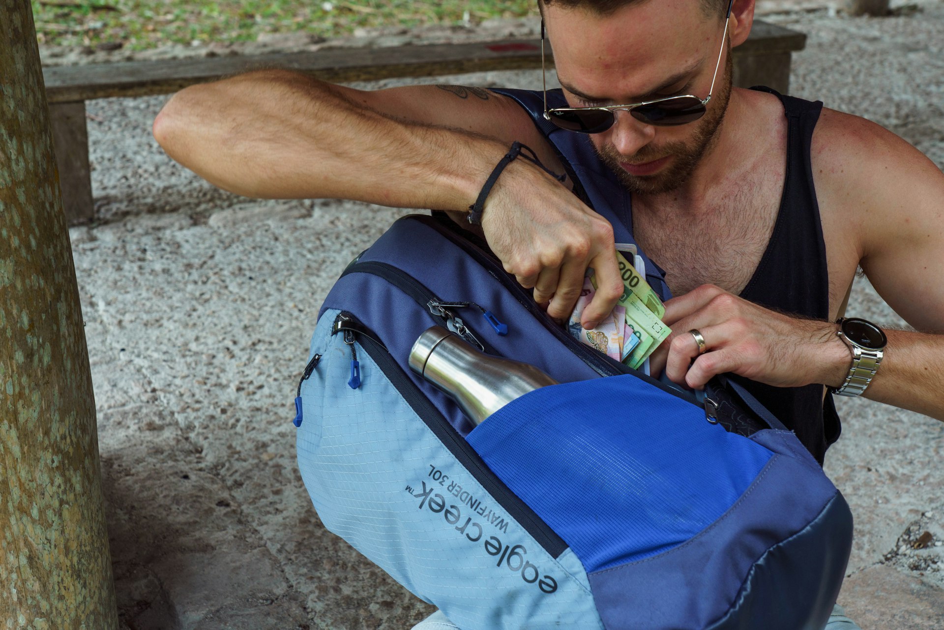A man extracts cash and a passport from a secret compartment in his backpack