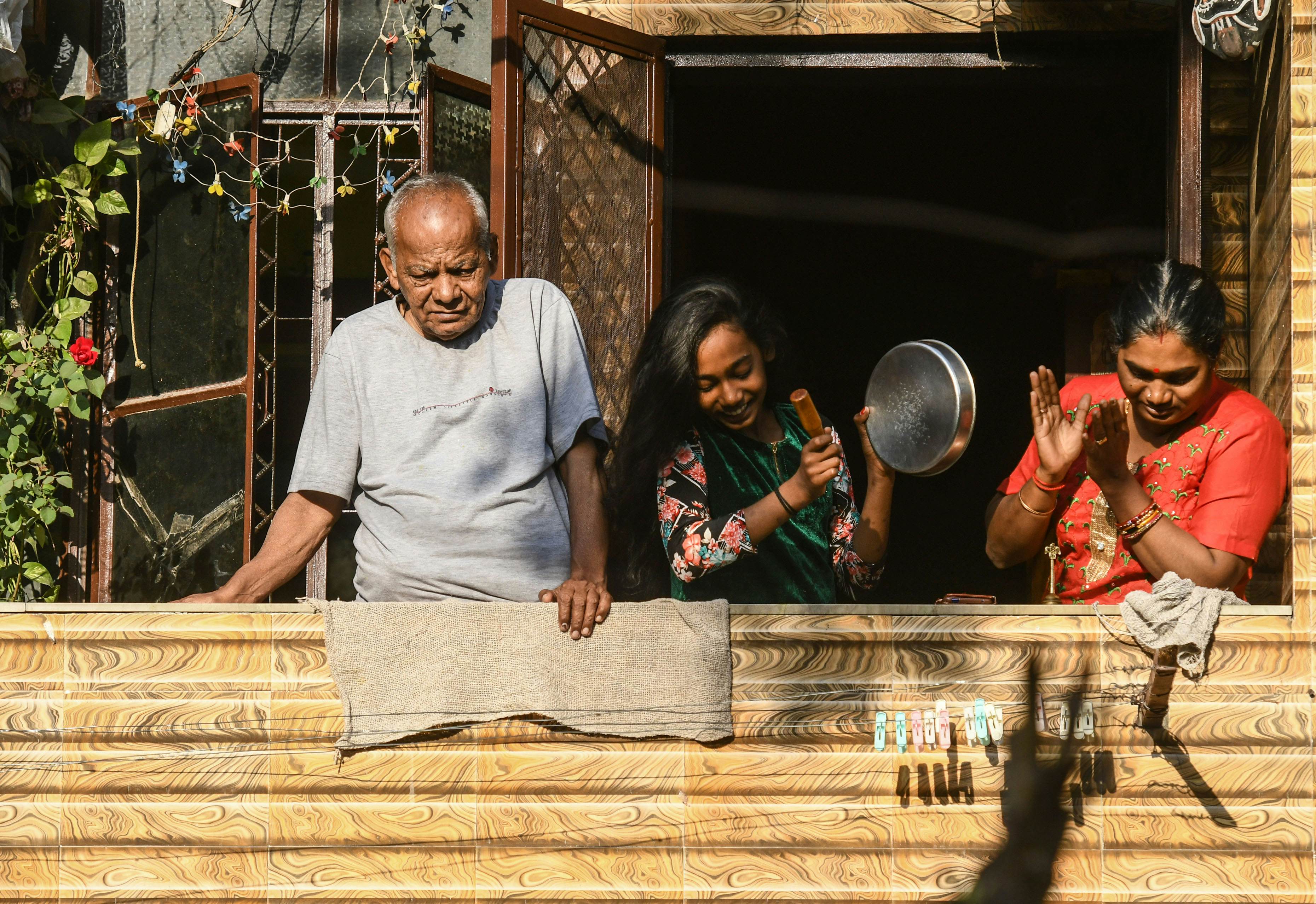 People in their balconies clap hands and beat utensils in a show of appreciation for those engaged in providing essential services to tackle the coronavirus, at Keshav Puram, on March 22, 2020 in New Delhi, India