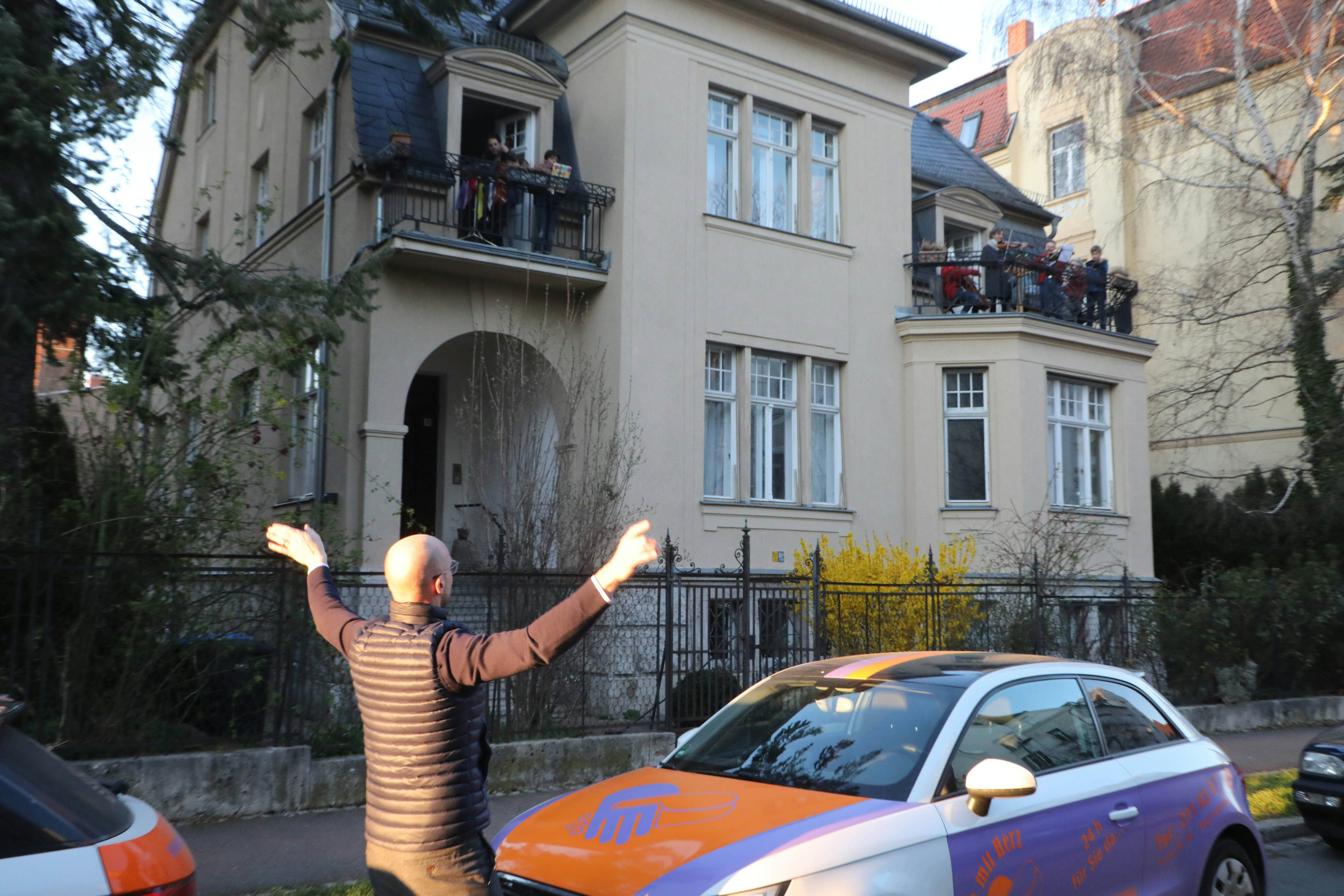 Johannes Kleinjung conducts residents playing the "Ode to Joy" on a balcony.
