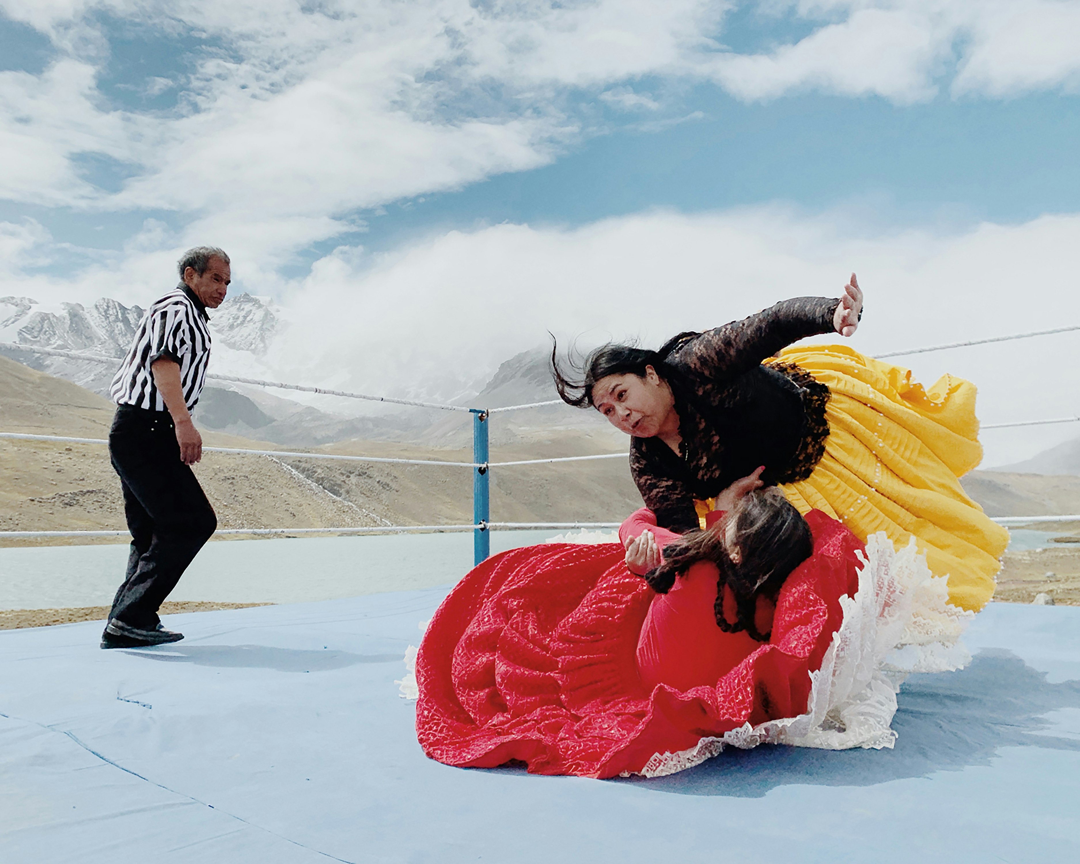 A Bolivian female wrestler performs in the ring while a referee looks on