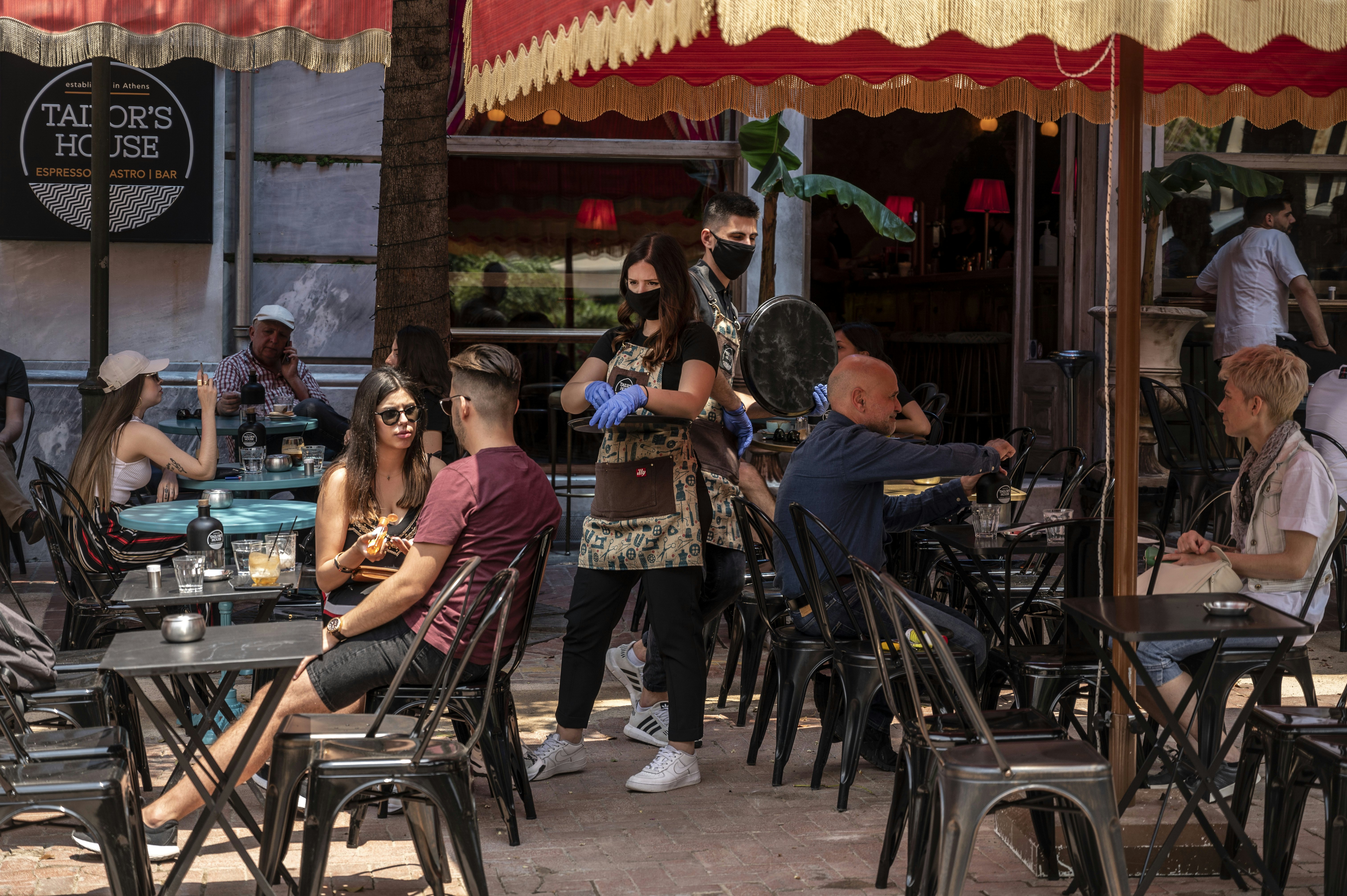 A waitress with a face mask and disposable gloves takes an order in a cafe