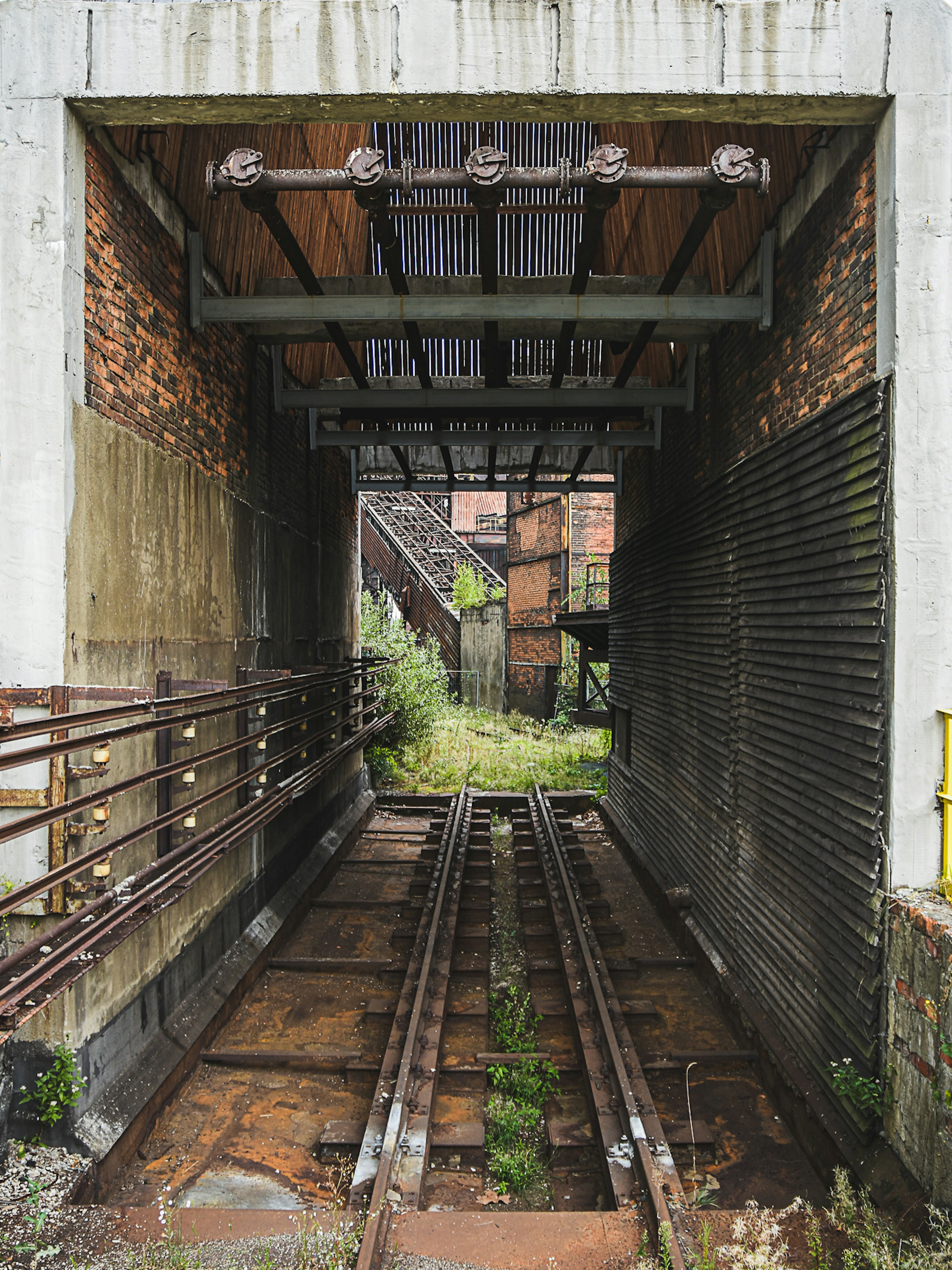 A narrow, short, derelict brick-built railway tunnel with rails running through it