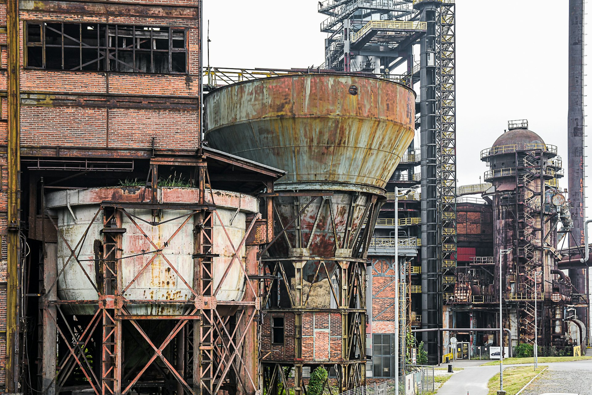 Industrial architecture covered in red-rust and clearly abandoned, including silos, warehouses and towers