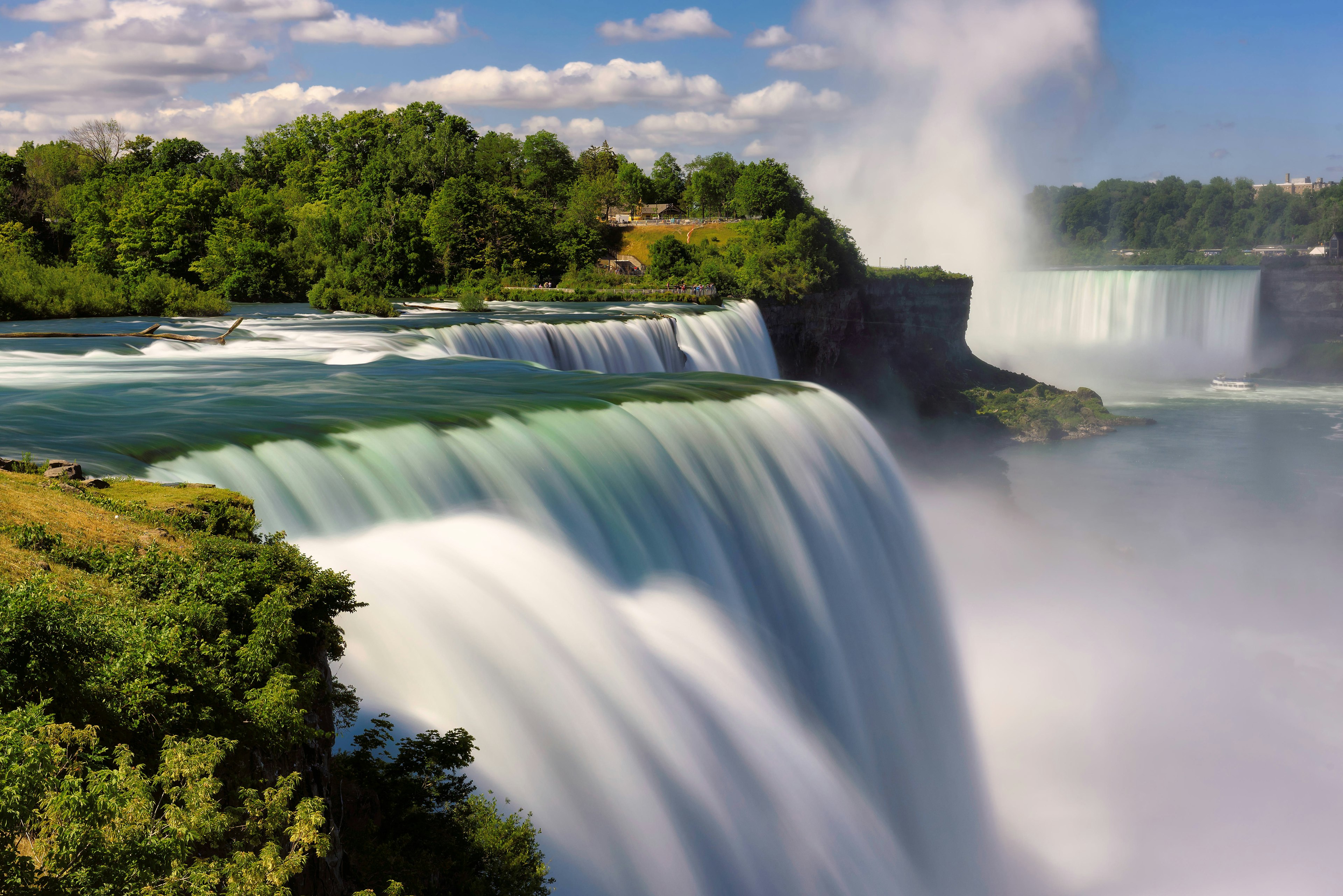 A landscape view of Niagara Falls in the spring or summer, as seen from the US side