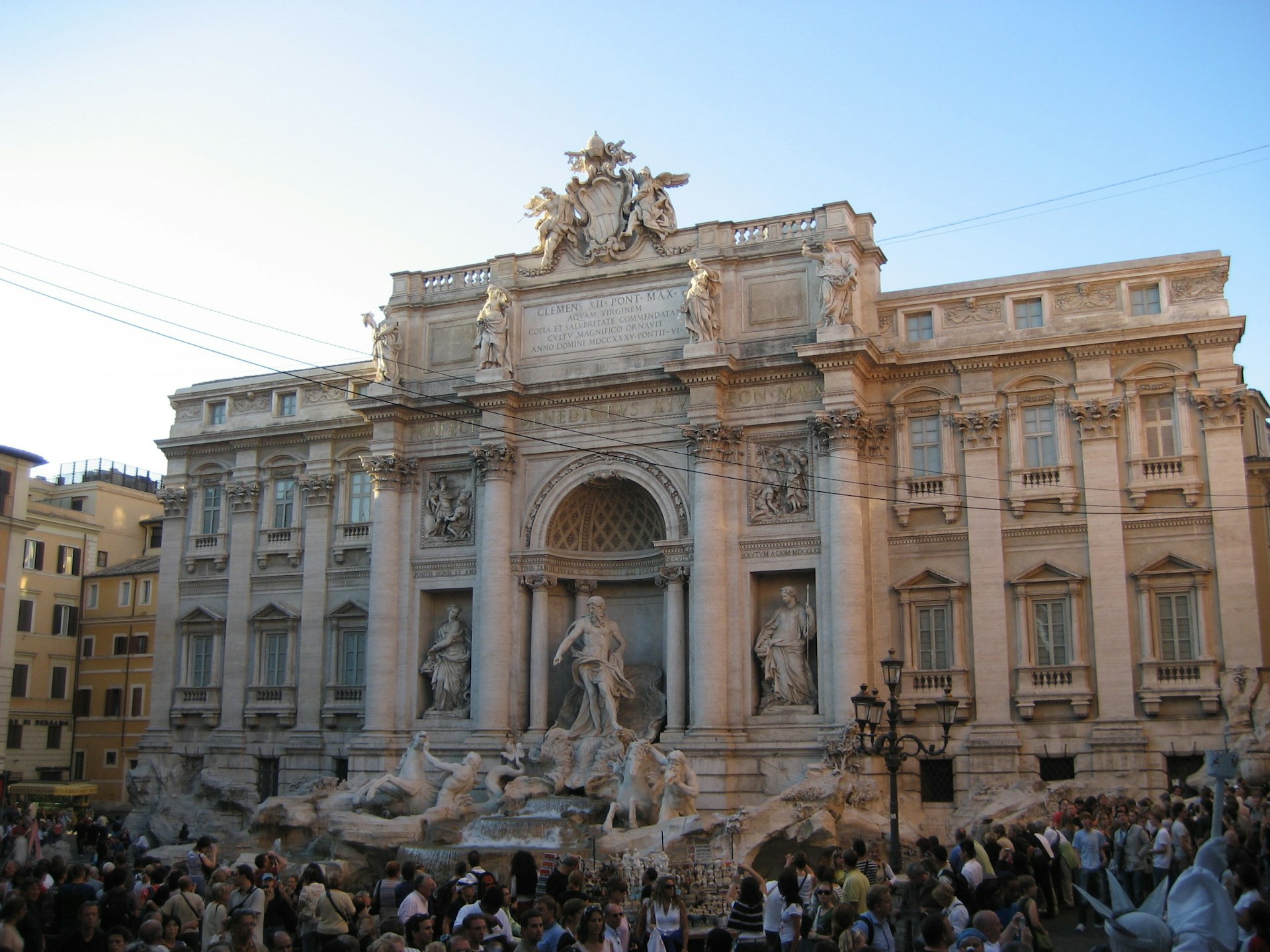 A crowd surrounds the intricate Trevi Fountain in Rome