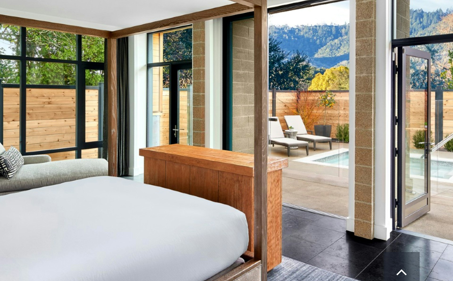 A large hotel room with a private plunge pool beyond floor-to-ceiling windows