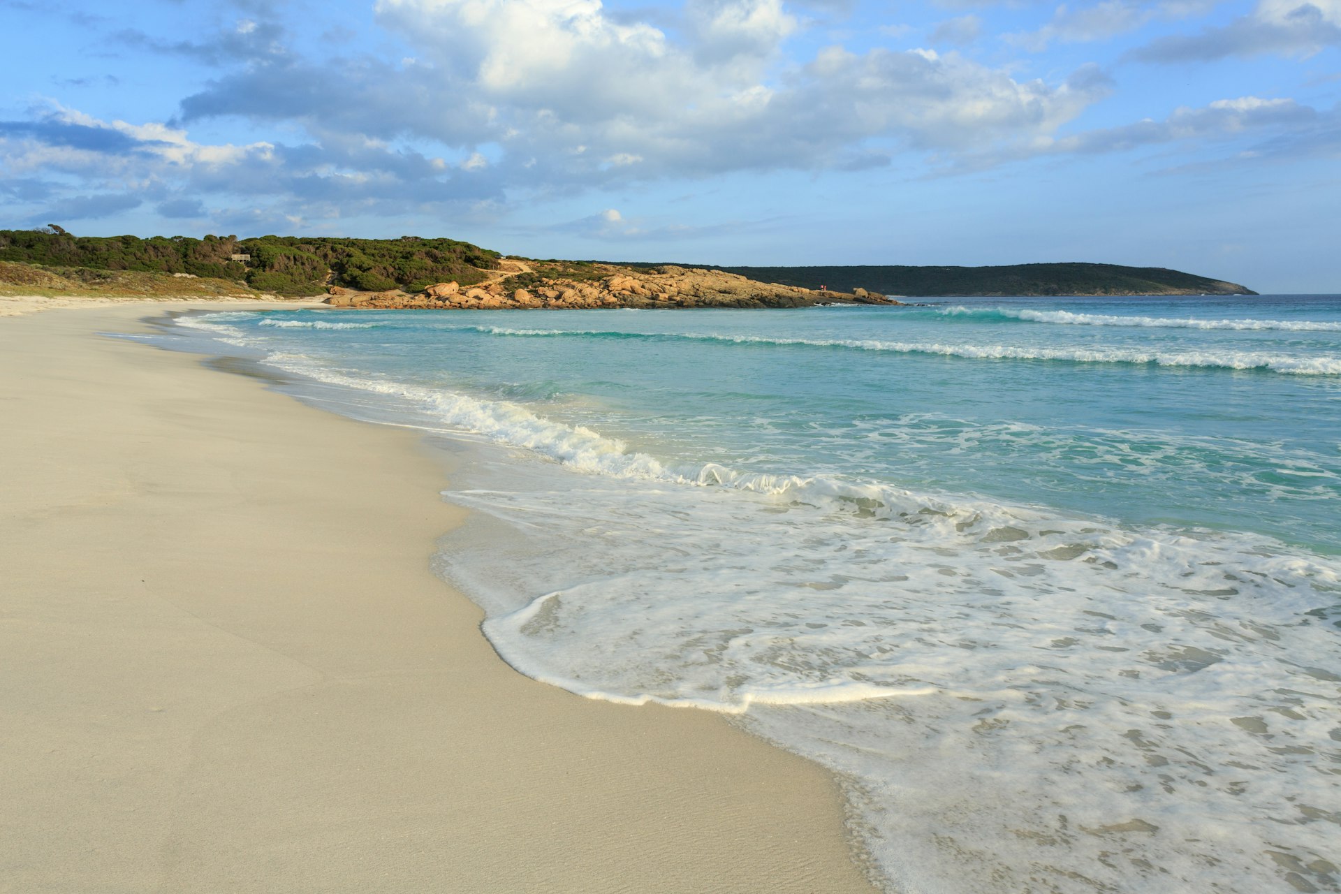 Waves lap on a light brown shore at Bremer Bay in Australia. 