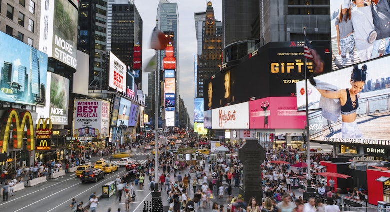 Crowds of people fill Times Square at low light.