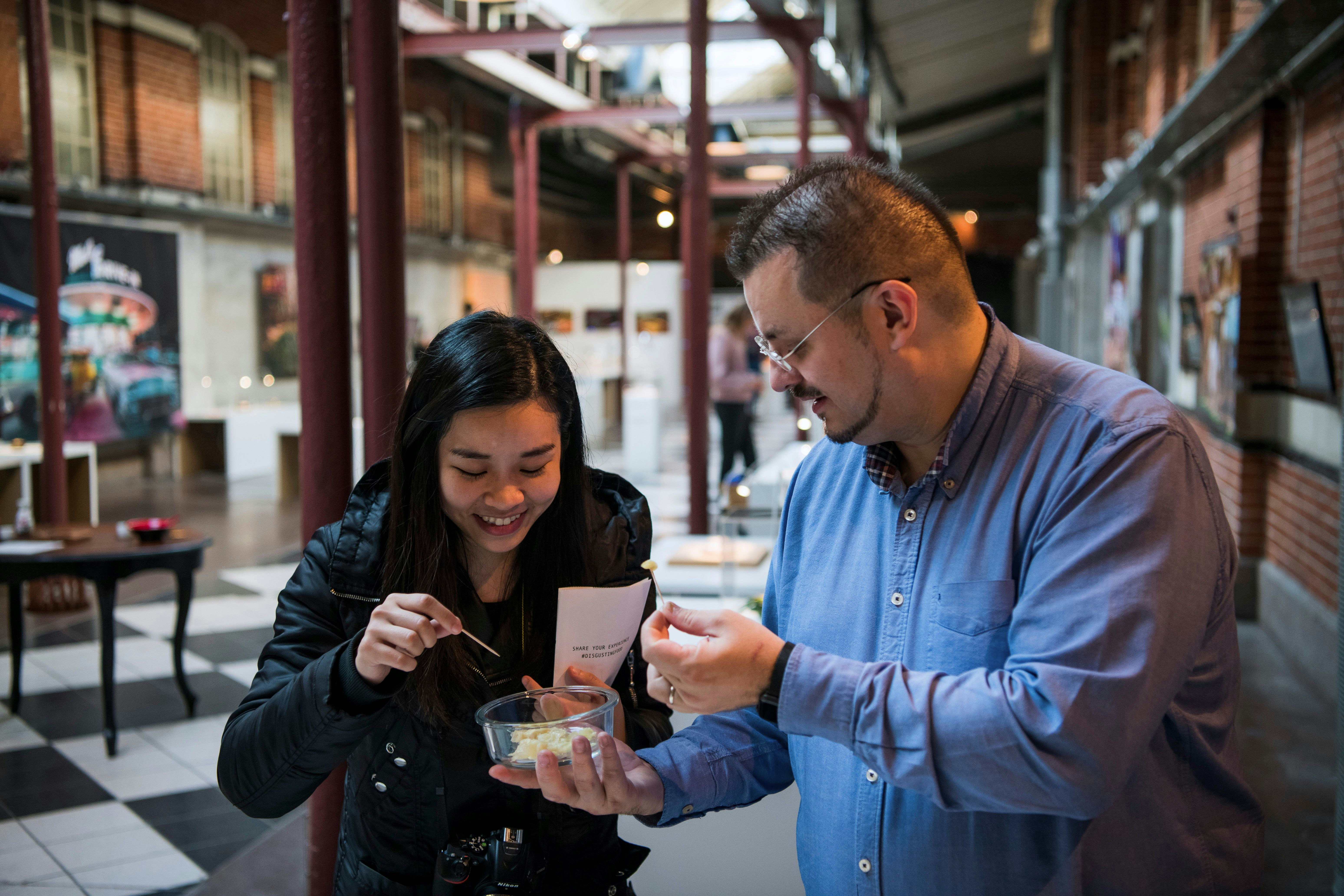 Andreas Ahrens (R), curator and museum director, and a visitor taste food at the Disgusting Food Museum