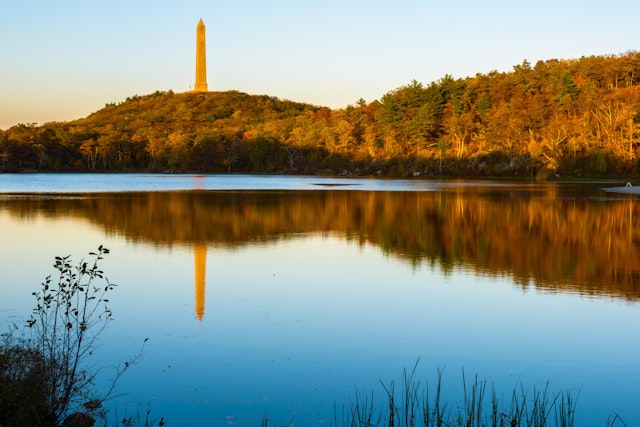A 1930s war monument is reflected in the lake on a fall evening at High Point State Park in New Jersey