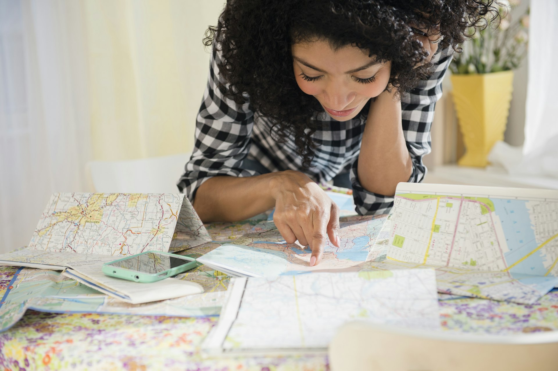 Mixed race woman planning a road trip with maps laid out on a table